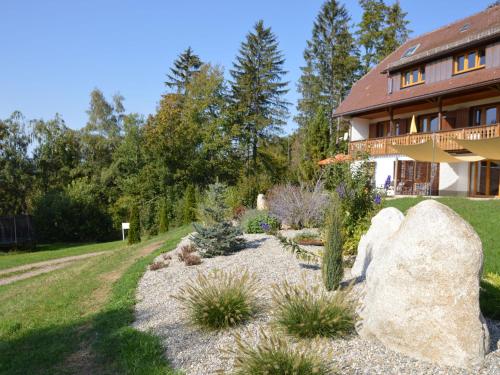 einen Garten vor einem Haus mit einem großen Felsen in der Unterkunft Large Apartment in Urberg in the black forest in Urberg