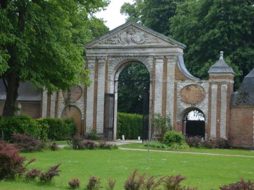 a large brick building with an arch in a yard at Holiday home in a historic building near Montreuil in Gouy-Saint-André