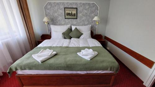 a bedroom with a large bed with towels on it at Komfort Hotel Platan in Harkány