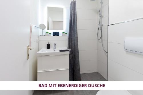 La salle de bains est pourvue d'un lavabo blanc et d'une douche. dans l'établissement Apartment Wahnfried No3 - citynah wohnen mit Küche und Duschbad, Parkplatz, 300m zur Fussgängerzone, à Bayreuth