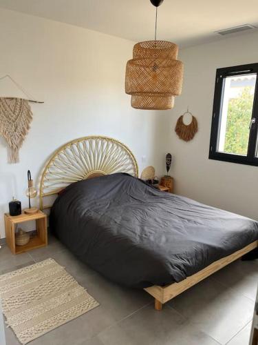 - une chambre avec un grand lit et une couverture noire dans l'établissement Jolie maison avec piscine, à Nissan-lez-Enserune