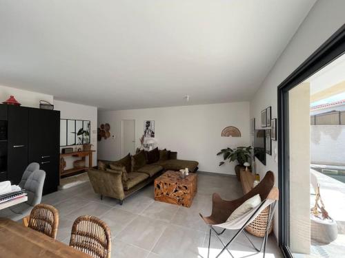 uma sala de estar com um sofá e uma mesa em Jolie maison avec piscine em Nissan-lez-Enserune