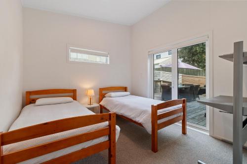 2 bedden in een kamer met een balkon bij Modern Kiwi Bach - Waihi Beach Holiday Home in Waihi Beach