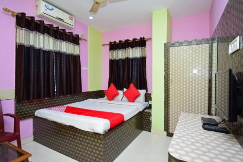 a bedroom with a bed with red pillows and a television at OYO Hotel Rajeswari in Rupnārāyanpur