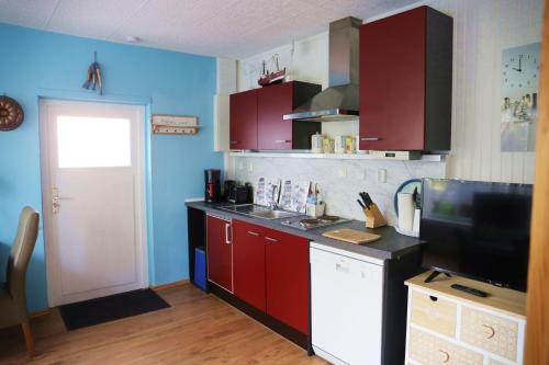 cocina con armarios rojos y encimera negra en Kos - Bungalow "Kapitänskajüte ", en Ostseebad Koserow