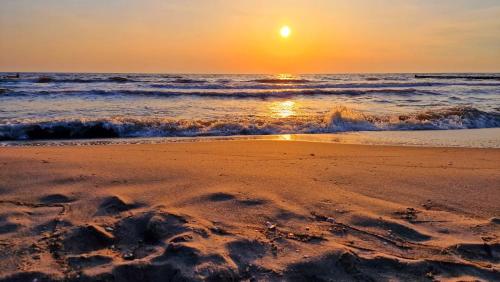 una puesta de sol en una playa con el océano en Kos - Bungalow "Kapitänskajüte ", en Ostseebad Koserow