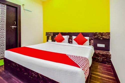 1 dormitorio con 1 cama grande con almohadas rojas en OYO Hotel Ambika Dx, en Gwalior