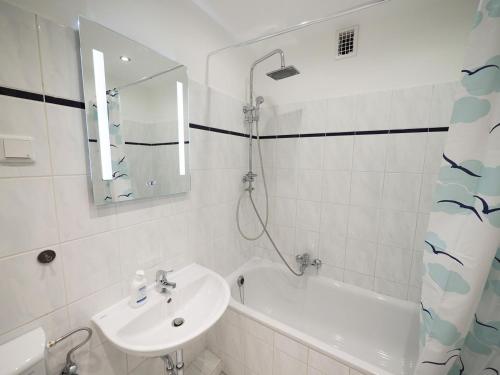 ein weißes Badezimmer mit einem Waschbecken, einer Badewanne und einem Spiegel in der Unterkunft Nice Apartment in Bargteheide (Hamburg) in Bargteheide