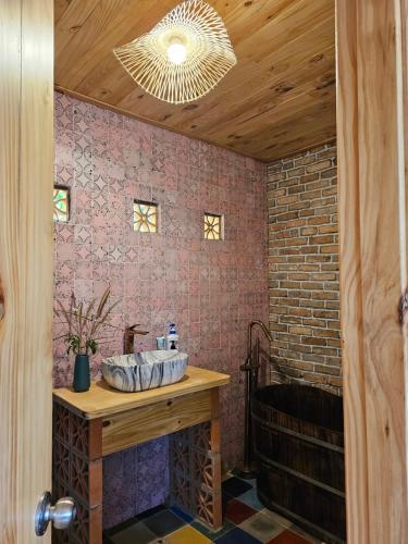 La salle de bains est pourvue d'un lavabo et d'un mur en briques. dans l'établissement Nhà Gạch cổ - Antique Brick House, à Bảo Lâm