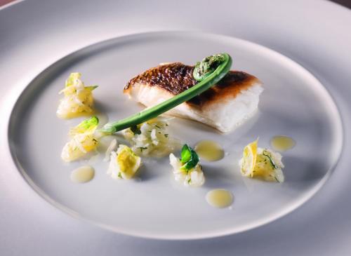 a white plate with a piece of fish and cauliflower at ANA InterContinental Appi Kogen Resort by IHG in Hachimantai