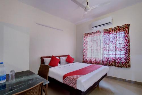 a bedroom with a bed and a red window at OYO Century Park in Kāsaragod