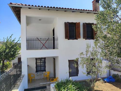 Cette maison blanche dispose d'un balcon avec des chaises jaunes. dans l'établissement ΔΙΑΚΟΠΕΣ ΣΤΗ ΘΑΣΟ ! ! !, à Theológos