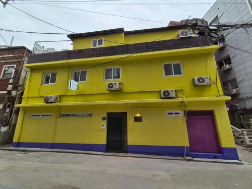 a yellow house with purple doors on a street at Ribini house in Seoul