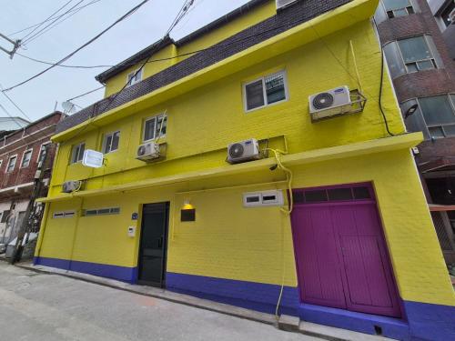 un bâtiment jaune avec une porte violette dans une rue dans l'établissement Ribini house, à Séoul