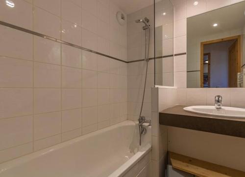 a bathroom with a bath tub and a sink at Charmant appartement « Les belles roches » Piscine in Notre-Dame-de-Bellecombe
