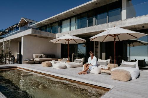 Un uomo seduto su un letto vicino alla piscina di Pure Sea Boutique Lodge a Gansbaai