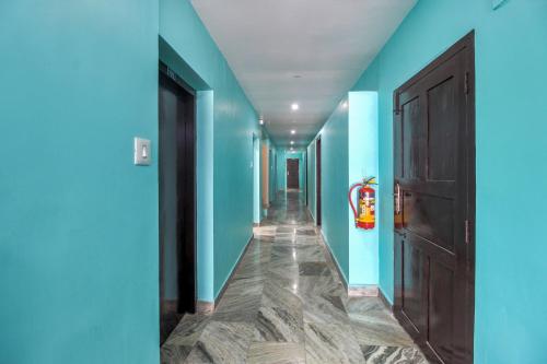 a corridor with blue walls and a brown door at Collection O Hotel Jaisas Paradise in Agastīswaram