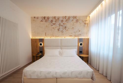 a bedroom with a large white bed and windows at Hotel Everest in Trento