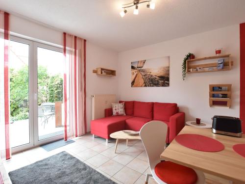 een woonkamer met een rode bank en een tafel bij Seaside Apartment in Insel Poel with Sauna in Timmendorf