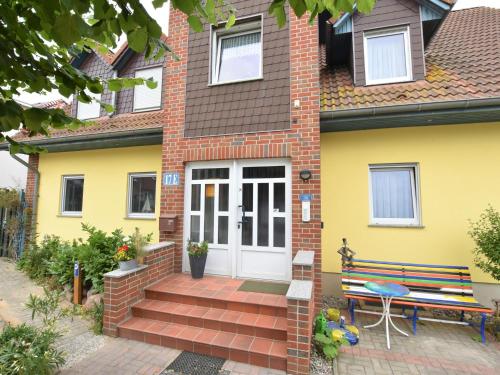 ein gelbes Haus mit einer Bank davor in der Unterkunft Seaside Apartment in Insel Poel with Sauna in Timmendorf