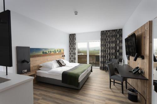 a bedroom with a bed and a table and a desk at Hotel Grohnder Fährhaus in Emmerthal