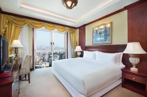 a bedroom with a large white bed and a window at Habtoor Metropolitan Palace Hotel in Beirut
