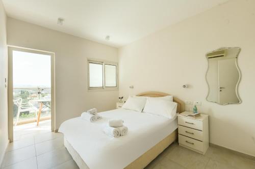 een witte slaapkamer met een groot bed en een raam bij Skyline 1BR Apartment with City and Sea View by Sea N' Rent in Herzelia 