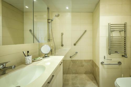 een badkamer met een bad, een wastafel en een douche bij Skyline 1BR Apartment with City and Sea View by Sea N' Rent in Herzelia 