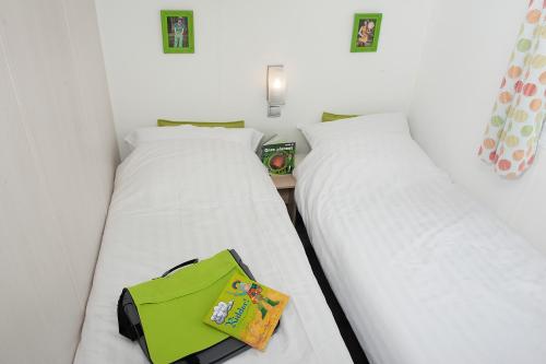 two beds in a room with a green bag at Happy Lodge in Alphen