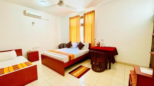 Cette chambre comprend 2 lits et une table. dans l'établissement Hotel Lihini Village Dambulla, à Dambulla