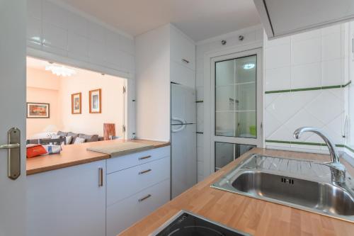 a kitchen with white cabinets and a stainless steel sink at Hoyo I by Ĥ - Isla Canela Golf GHHI16IA3P78 in Isla Canela