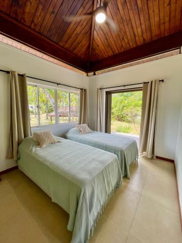 two beds in a bedroom with a large window at Pae Miti Beach house - white sand beach - Tahiti - 7 people in Punaauia