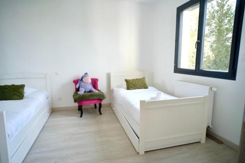- une chambre avec deux lits et une chaise avec un ours en peluche dans l'établissement Villa Zara, à Démouville