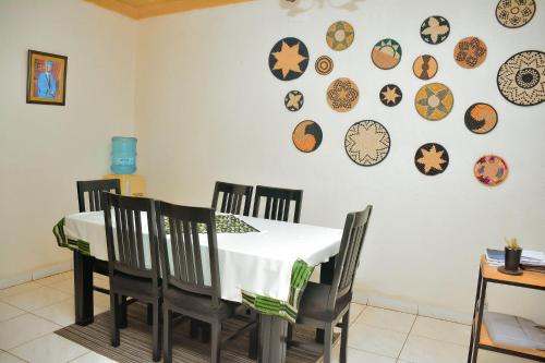 uma sala de jantar com uma mesa e cadeiras e pratos na parede em Tranquil Retreat em Kigali