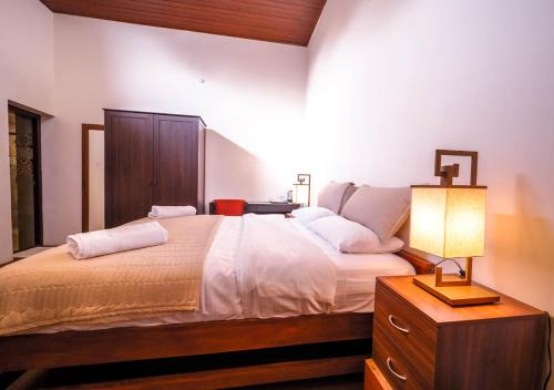 a bedroom with a bed with a lamp on a dresser at Lauriston Ooty Town Heritage Bungalow by VOYE HOMES in Ooty