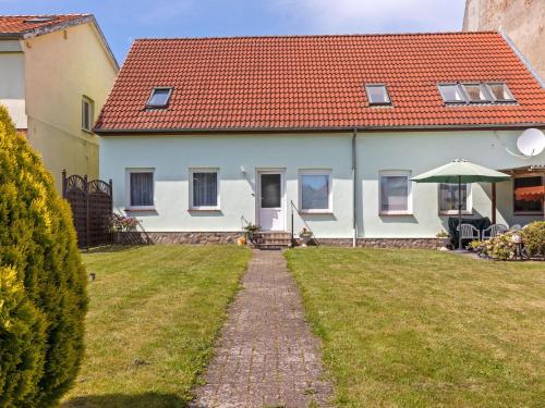 a house with a red roof and a grass yard at Attractive Apartment in Kl tz near the Sea in Klütz