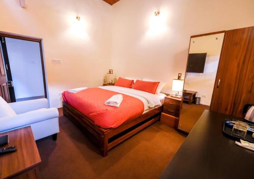 a bedroom with a bed with orange sheets and a mirror at Lauriston Ooty Town Heritage Bungalow by VOYE HOMES in Ooty