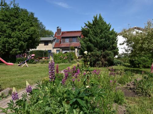 einen Garten mit lila Blumen und einem Spielplatz in der Unterkunft Beautiful Apartment in Robertsdorf with Garden in Blowatz