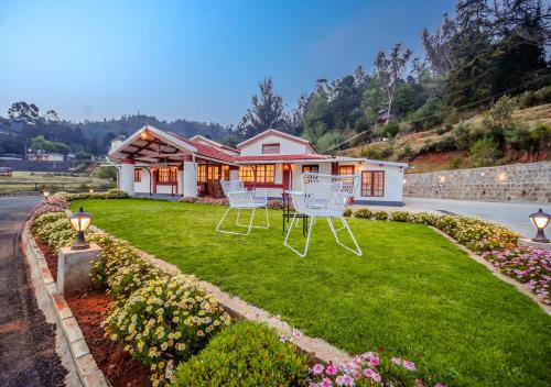 a house with two lawn chairs in the yard at Lauriston Ooty Town Heritage Bungalow by VOYE HOMES in Ooty