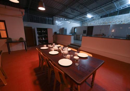 a long wooden table in a large room with chairs at Lauriston Ooty Town Heritage Bungalow by VOYE HOMES in Ooty