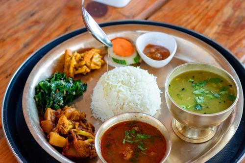 a plate of food with rice and different types of food at Naya Gaun Eco Resort in Pokhara