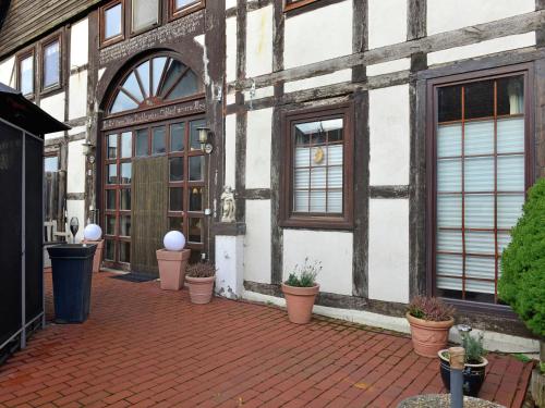 a building with potted plants on a brick patio at Cozy Apartment in L wensen Lower Saxony with Private Terrace in Bad Pyrmont