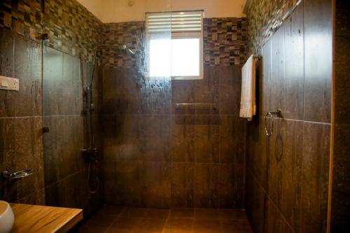 a bathroom with a shower with a glass door at Sharta Yala in Tissamaharama