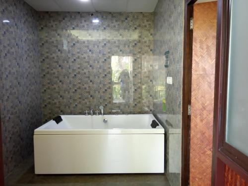 a white bath tub in a bathroom with tiles at Discovery Village Resorts in Begūr
