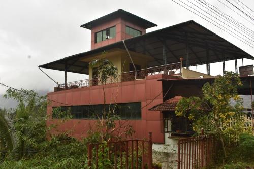 un edificio rojo con balcón en la parte superior en OYO Home Inn Of Dreams Homestay, en Wayanad