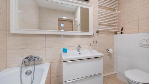 La salle de bains est pourvue d'un lavabo, de toilettes et d'un miroir. dans l'établissement Apartamenty Sun & Snow Angel City, à Cracovie