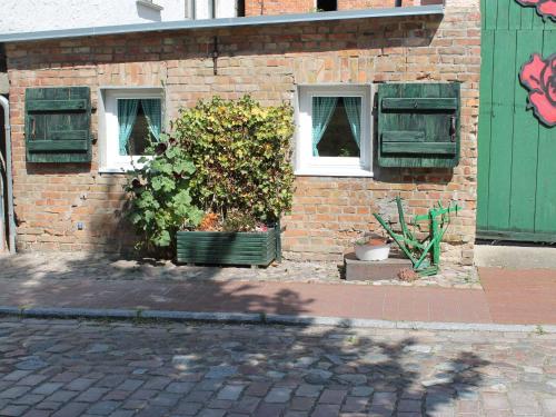 a brick building with two windows and a bush at Beautiful Apartment in Damgarten with Garden in Ribnitz-Damgarten