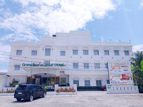 a van parked in front of a white building at Grand Buana Lestari Hotel in Duku