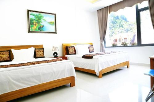 two beds in a room with white walls at Phong Nha Jasmine Hostel & Roof Top Bar in Phong Nha
