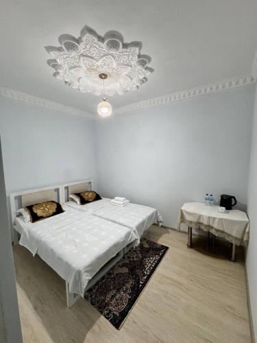 Dieses weiße Zimmer verfügt über 2 Betten und einen Kronleuchter. in der Unterkunft Boulevard Architectural Hotel Wifi 100 MBS in Buxoro